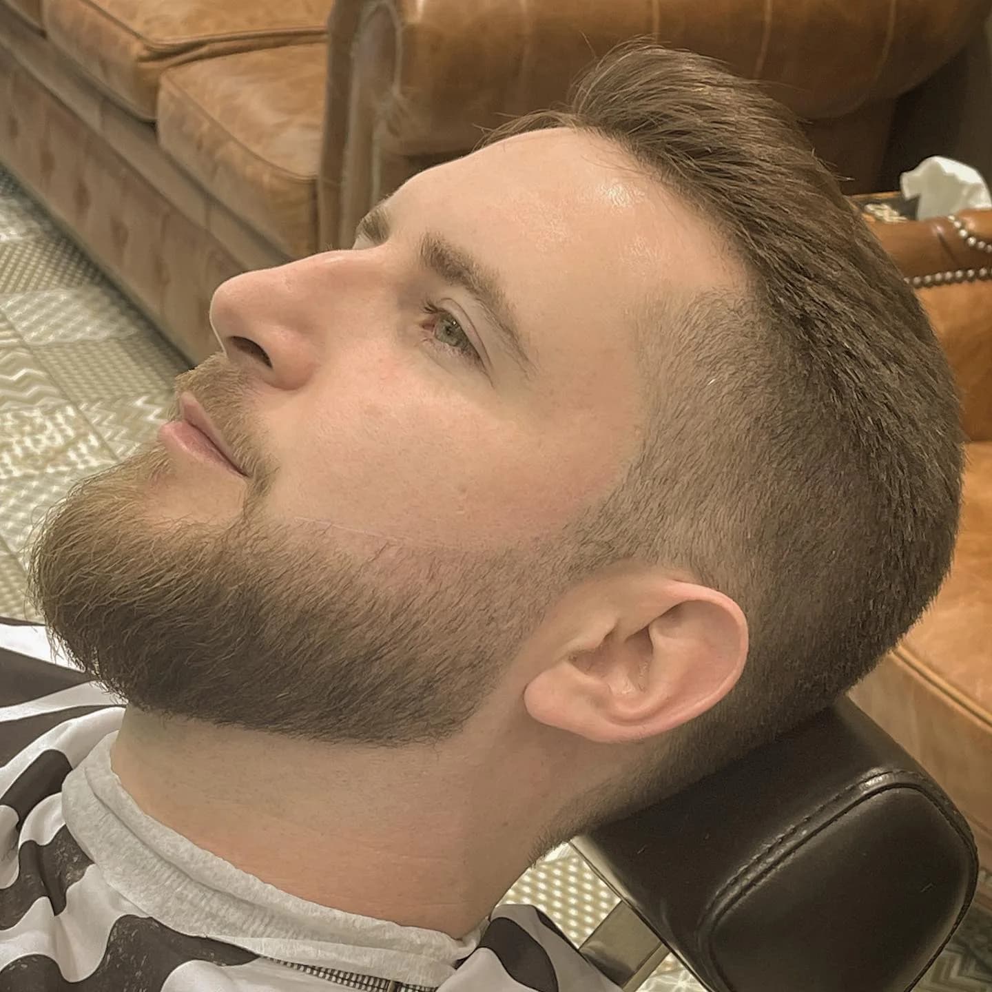 Profil d’un client à la barbe fraîchement taillée, installé dans le fauteuil