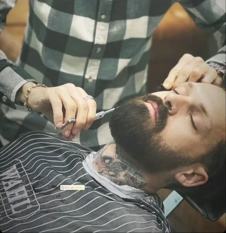 Taille de barbe à la tondeuse sur un client barbu, au salon